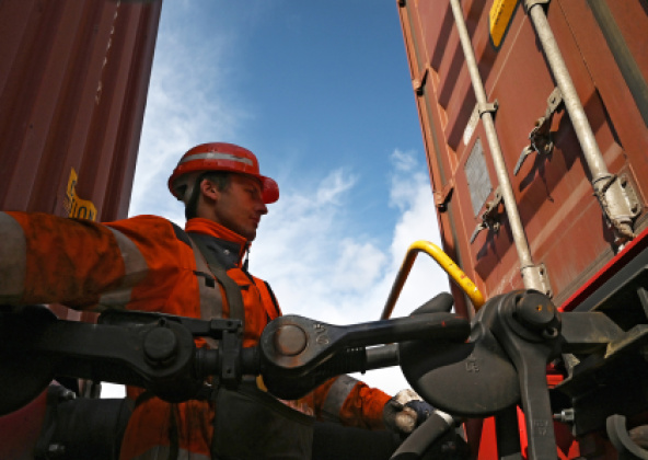 Mitarbeiter in Arbeitskleidung beim Kuppeln von Güterwagen